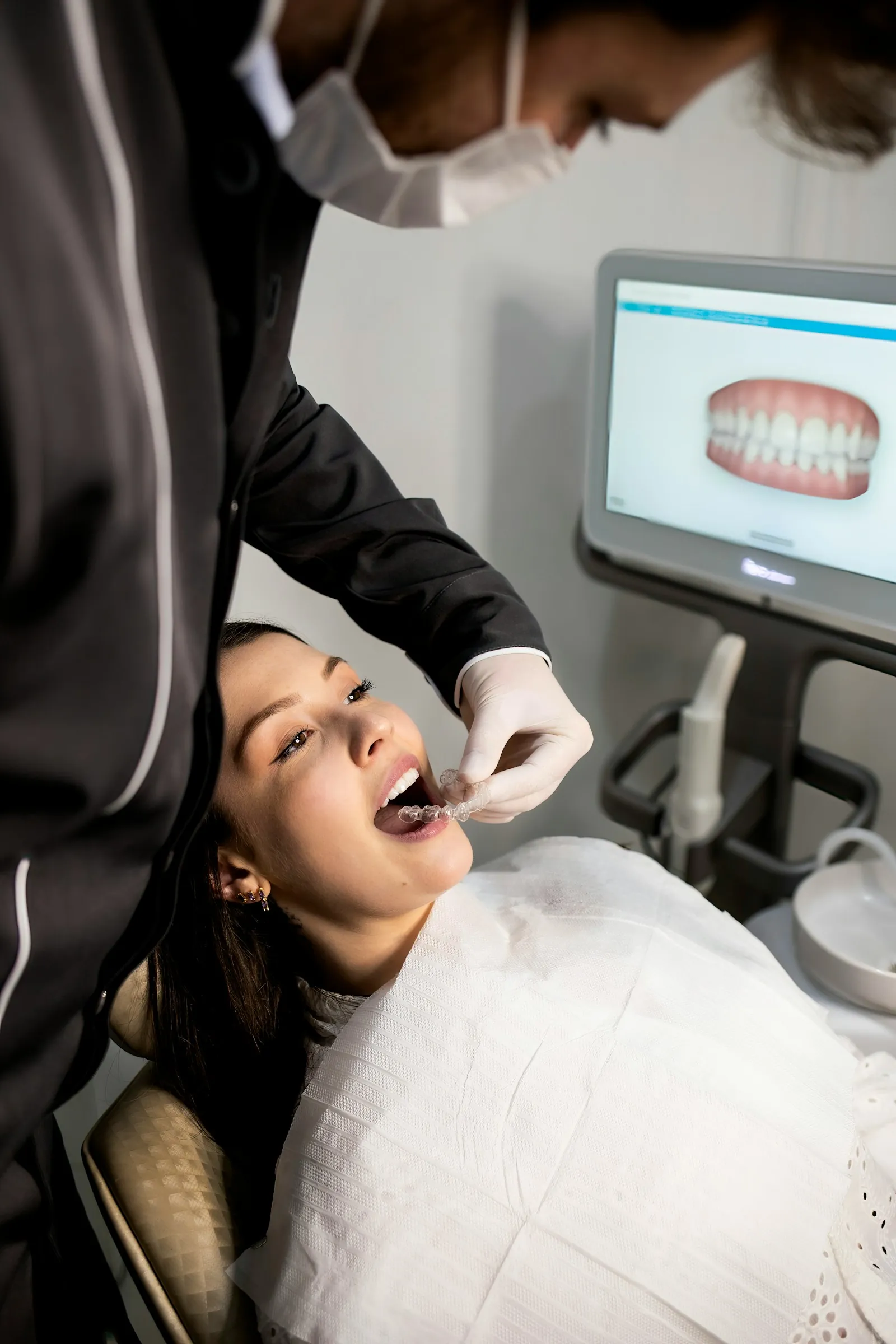 Dentista encaixando um alinhador com o modelo 3D da arcada na tela
